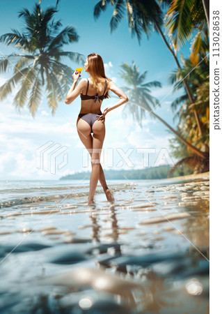 Rear view portrait of young, slim woman in bikini sunbathing on tropical beach drinking refreshing cocktail and admire views and landscapes of nature. 113028638