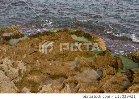 A rocky beach with seaweed and waves lapping on it A rocky beach with seaweed and waves lapping on it 113029421