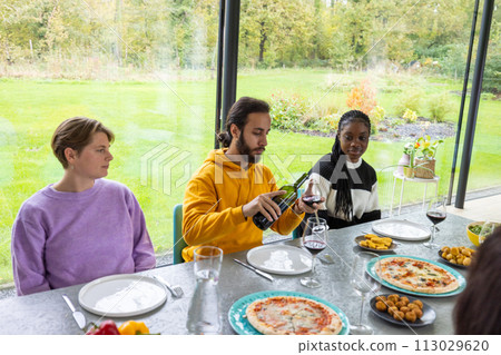 Friends Enjoying a Wine and Dine Experience in a Greenhouse Setting Friends Enjoying a Wine and Dine Experience in a Greenhouse Setting 113029620
