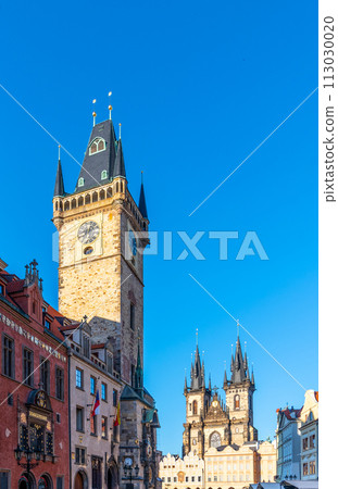 The historic clock tower stands tall against a clear blue sky in Prague Old Town Square, with other Gothic architecture visible in the background. Prague, Czechia 113030020