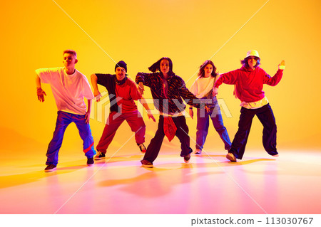 Dancers in dynamic motion, shows contemporary hip-hop dance styles in neon light against gradient colorful studio background. 113030767
