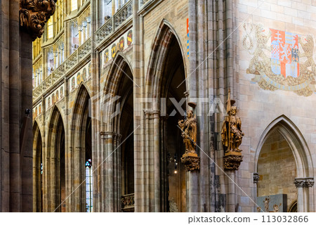 The vaulted ceilings and gothic arches of Saint Vitus Cathedrals interior are showcased, accented by heraldic banners and intricate sculptures. Prague Castle, Prague, Czechia 113032866