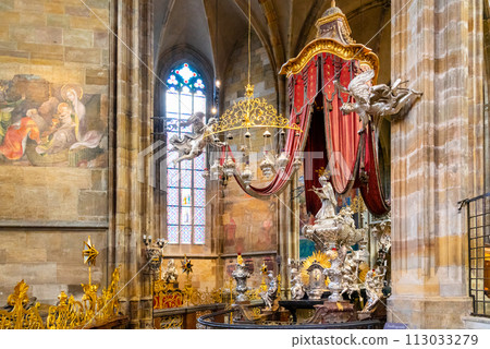 The ornate canopy of St. John of Nepomuk silver tomb, with its red drapery and intricate details, stands within the grand interior of Saint Vitus Cathedral. Prague, Czechia The ornate canopy of St. John of Nepomuk silver tomb, with its red drapery and intricate details, stands within the grand interior of Saint Vitus Cathedral. Prague, Czechia 113033279