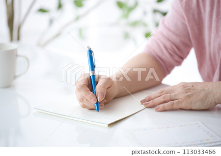 Hand of a middle-aged woman writing a letter 113033466