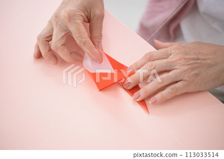 Hands of a middle-aged woman folding origami Hands of a middle-aged woman folding origami 113033514
