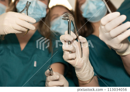 Hands of dentist surgeons with forceps and instruments for dental treatment Hands of dentist surgeons with forceps and instruments for dental treatment 113034056