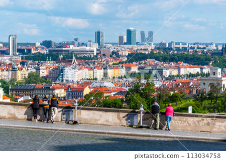 Visitors looking out over the modern skyline of Pankrac set against the historical backdrop of Prague, with lush greenery under a dynamic sky. Prague, Czechia Visitors looking out over the modern skyline of Pankrac set against the historical backdrop of Prague, with lush greenery under a dynamic sky. Prague, Czechia 113034758