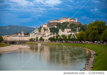 Salzburg, Austria, August 15, 2022. Golden hour shot towards the historic center. Highlighted is the fort at the top of the hill which dominates the landscape. Salzburg, Austria, August 15, 2022. Golden hour shot towards the historic center. Highlighted is the fort at the top of the hill which dominates the landscape. 113034802