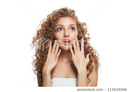 Surprised young woman with natural make-up, clear fresh skin and wavy hairstyle on white background 113034946