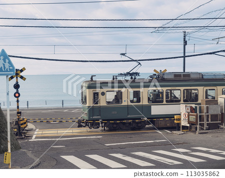 江之電列車在神奈川縣鎌倉市鎌倉高校前站的海濱鐵路道口行駛 113035862
