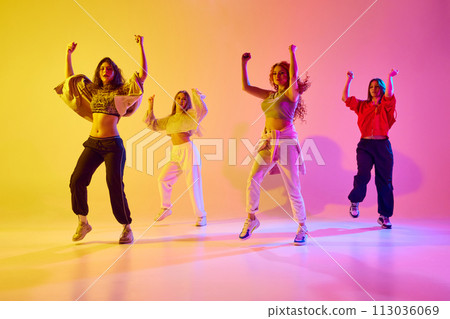 Stylish young women in sport style casual clothe sin motion, dancing hip hop, contemp against gradient background in neon light Stylish young women in sport style casual clothe sin motion, dancing hip hop, contemp against gradient background in neon light 113036069