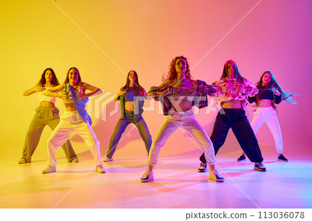 Artistic, talented young women in motion, dancing street style dance against gradient background in neon light 113036078