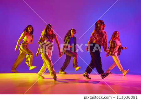 Dynamic image of young talented women in casual clothes in motion, dancing street style dance against gradient background in neon light Dynamic image of young talented women in casual clothes in motion, dancing street style dance against gradient background in neon light 113036081