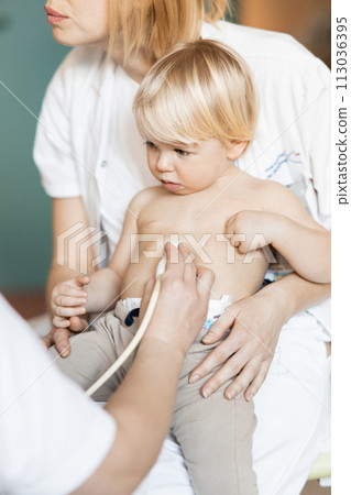 Small child being checked for heart murmur by heart ultrasound exam by cardiologist as part of regular medical checkout at pediatrician 113036395