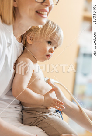 Small child being checked for heart murmur by heart ultrasound exam by cardiologist as part of regular medical checkout at pediatrician 113036406