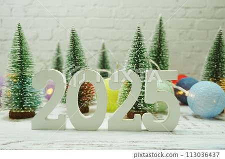 Happy New Year 2025 festive background with christmas tree on white brick wall background Happy New Year 2025 festive background with christmas tree on white brick wall background 113036437