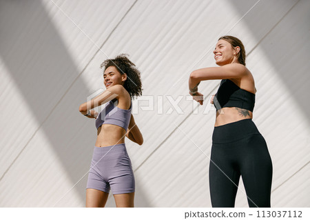 Young sportswomen in tracksuit are stretching outdoor and preparing to jogging. Healthy life concept 113037112