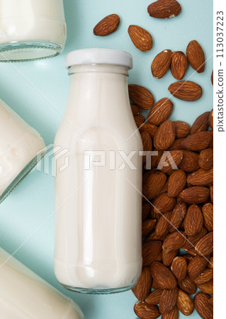 Almond nut milk in a glass bottle on a blue background top view. 113037223