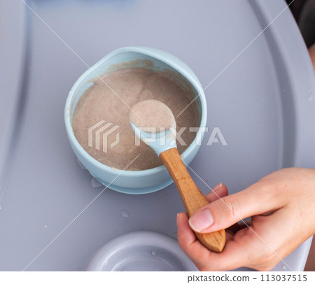 Buckwheat porridge for children in a plate. Feeding children healthy porridge, close-up 113037515