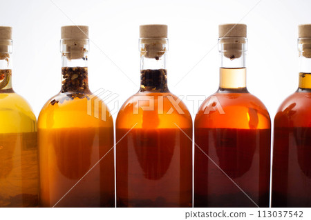 Many bottles with brown transparent alcoholic drink. Homemade tinctures based on natural herbs. Liquor and traditional vodka, collection Many bottles with brown transparent alcoholic drink. Homemade tinctures based on natural herbs. Liquor and traditional vodka, collection 113037542