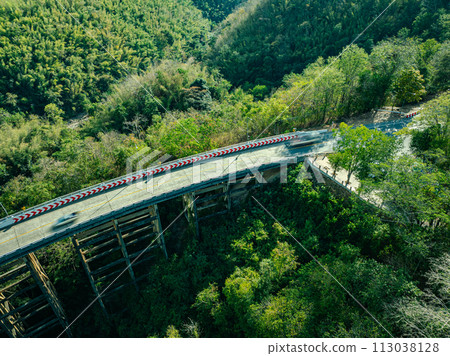 .Bridge over forest river under blue sky with green landscape and mountain view with trees.. 113038128