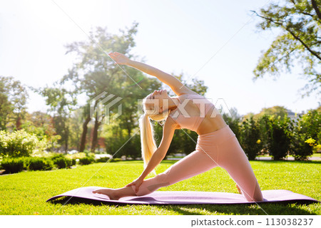 Young woman doing excercise at the public park. Fitness woman doing yoga exercises in the morning. Young woman doing excercise at the public park. Fitness woman doing yoga exercises in the morning. 113038237