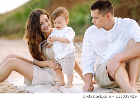 Cheerful young family with little baby boy spending time together on the beach. 113038429