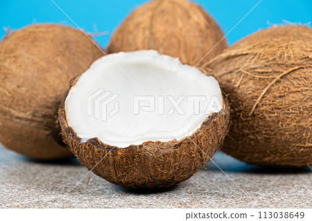 Whole coconuts and half a coconut on a blue and gray background close-up Whole coconuts and half a coconut on a blue and gray background close-up 113038649