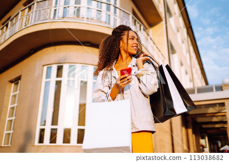 Young woman with shopping bags walking on street. Sale, shopping and happy people concept. 113038682