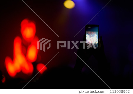 Hand with a phone records live music festival. People taking photographs with smart phone during concert. Hand with a phone records live music festival. People taking photographs with smart phone during concert. 113038962