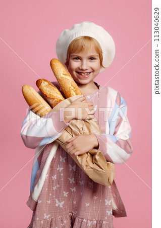 Joyful girl jumping with a bag of bread on a pink background Joyful girl jumping with a bag of bread on a pink background 113040629