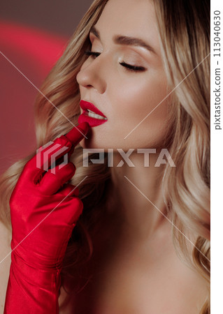 A woman applies red lipstick. Close-up side view. A woman applies red lipstick. Close-up side view. 113040630