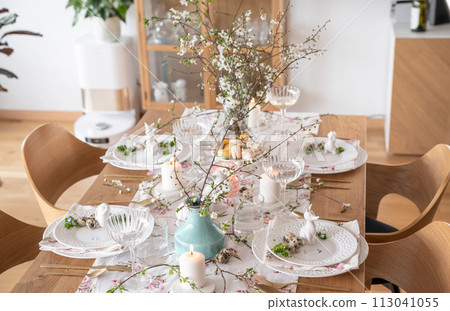 Spring Easter decor. Easter table setting. Flowers and dishes and candles for a festive dinner 113041055