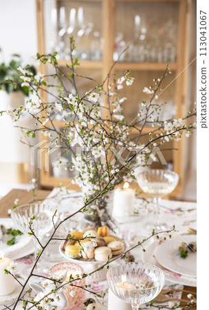 Spring Easter decor. Easter table setting. Flowers and dishes and candles for a festive dinner 113041067