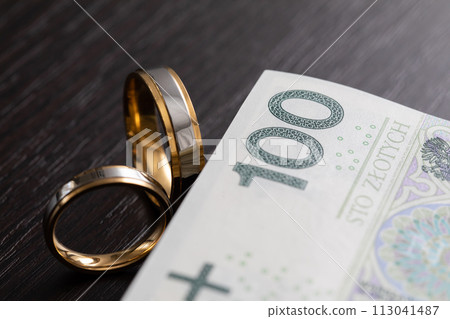 Gold wedding rings surrounded by a stack of Polish banknotes. Gold wedding rings surrounded by a stack of Polish banknotes. 113041487
