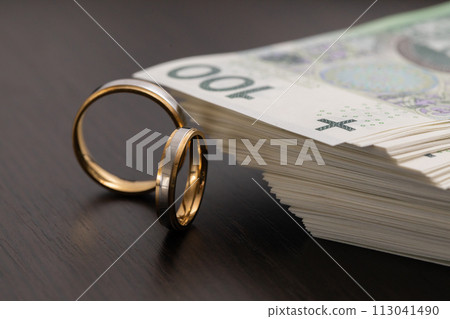 Gold wedding rings surrounded by a stack of Polish banknotes. 113041490