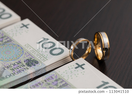 Gold wedding rings surrounded by a stack of Polish banknotes. Gold wedding rings surrounded by a stack of Polish banknotes. 113041510