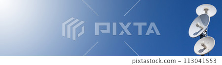 Several telecommunications antennas of a cellular network and wireless internet against a blue sky. Receiving and digitizing multiple pieces of information at once. Panoramic frame. Blue background. Several telecommunications antennas of a cellular network and wireless internet against a blue sky. Receiving and digitizing multiple pieces of information at once. Panoramic frame. Blue background. 113041553
