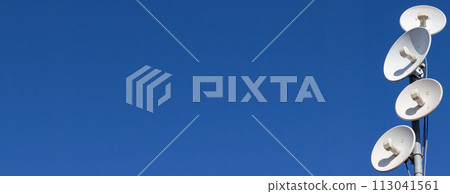 Several telecommunications antennas of a cellular network and wireless internet against a blue sky. Receiving and digitizing multiple pieces of information at once. Panoramic frame. 113041561