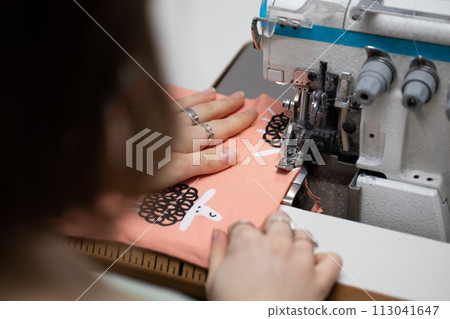 A young schoolgirl learns to sew face masks during a pandemic on an overlock sewing machine. A young schoolgirl learns to sew face masks during a pandemic on an overlock sewing machine. 113041647