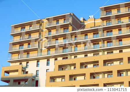 A high multi-family apartment block against a blue sky. A high multi-family apartment block against a blue sky. 113041715