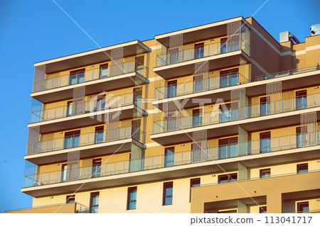 A high multi-family apartment block against a blue sky. A high multi-family apartment block against a blue sky. 113041717