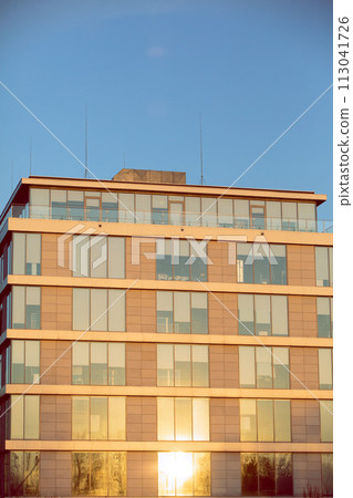 A high multi-family apartment block against a blue sky. A high multi-family apartment block against a blue sky. 113041726