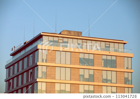 A high multi-family apartment block against a blue sky. 113041728