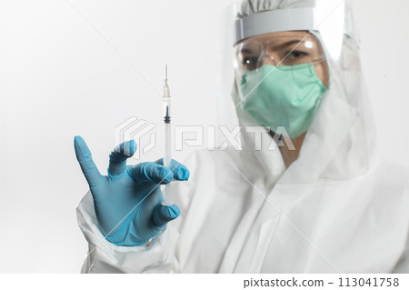 A young apprentice wearing a mask and protective suit is holding a syringe in her hand. 113041758