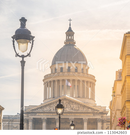 The Pantheon in Paris bathed in the warm glow of a setting sun, with street lamps and a clear sky. Paris, France 113042603
