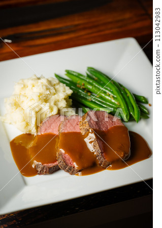 pouring brown gravy sauce on roasted beef pouring brown gravy sauce on roasted beef 113042983