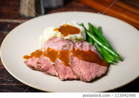 pouring brown gravy sauce on roasted beef pouring brown gravy sauce on roasted beef 113042990