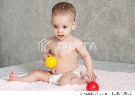 The child froze in delight and throws away the colored balls he is playing with 113043061
