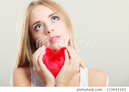 Sad unhappy woman holding red heart pillow 113043103